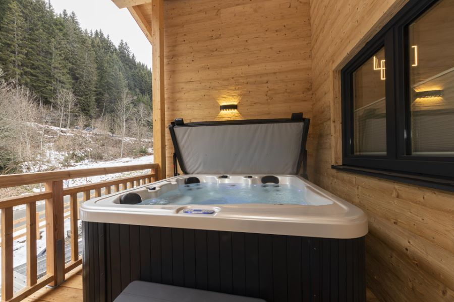 Whirlpool auf einer Holzterrasse mit Blick auf einen bewaldeten Hang