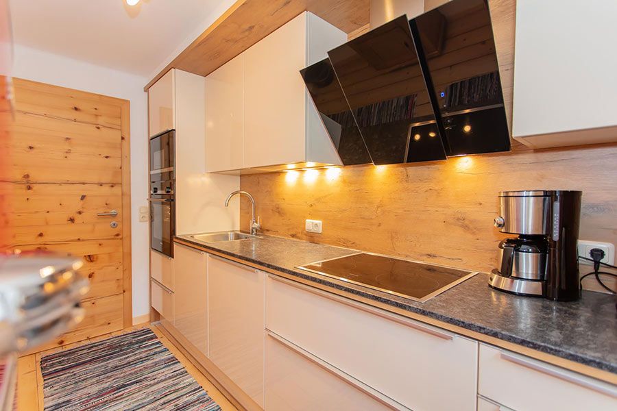 Modern kitchen countertop with built-in stovetop, sink, coffee maker, and overhead cabinets with under-cabinet lighting