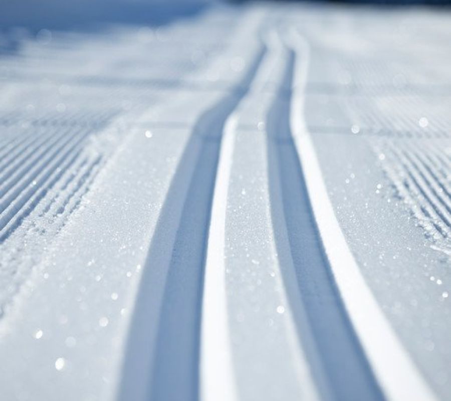 Nahaufnahme von parallelen Langlaufspuren im frisch präparierten Schnee